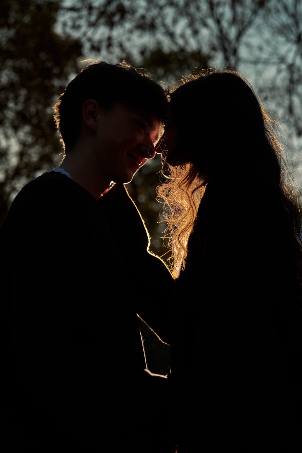 A couple standing close together in backlight