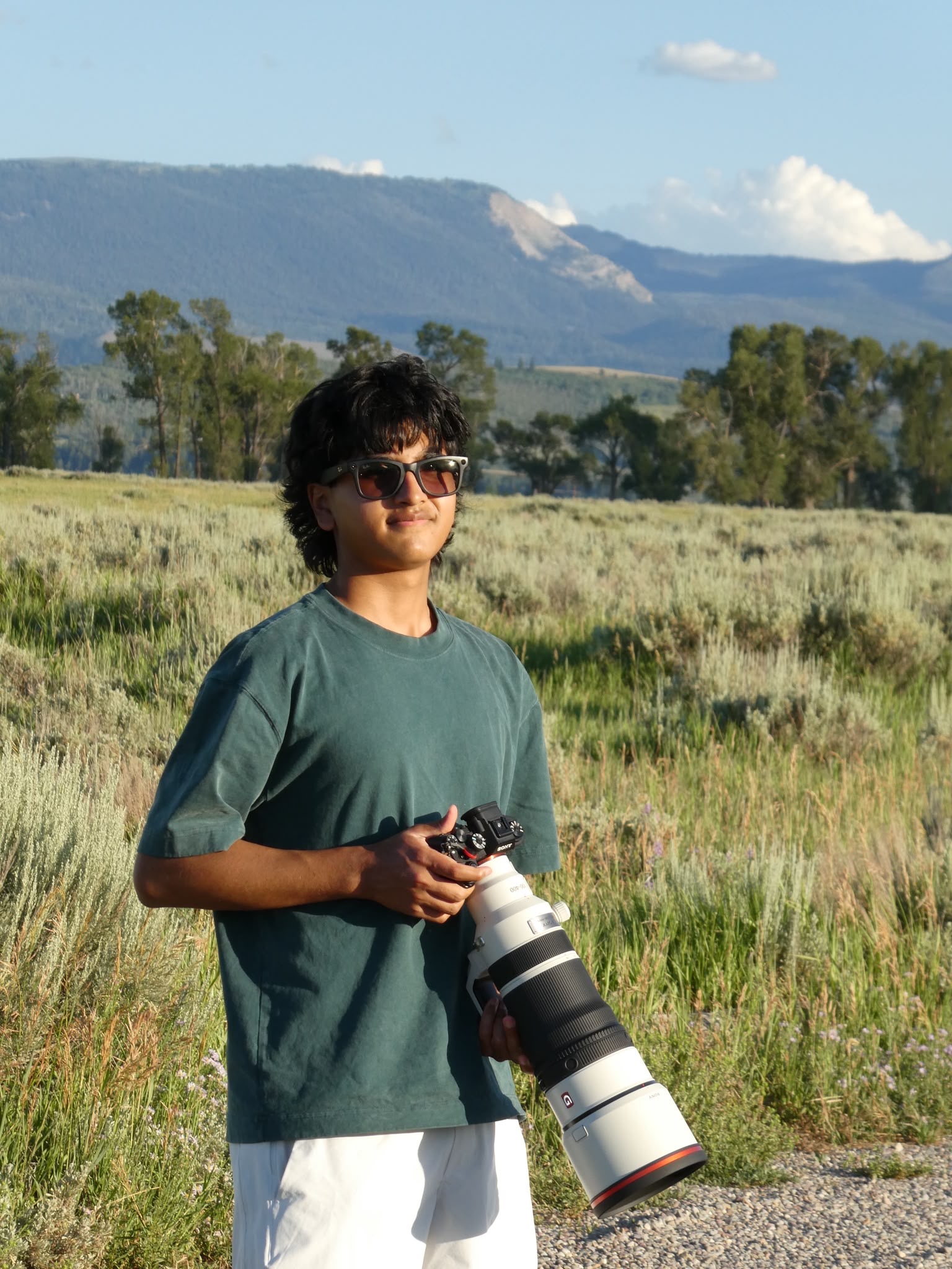 Dutt Vyas holding his camera outdoors with mountains in the background