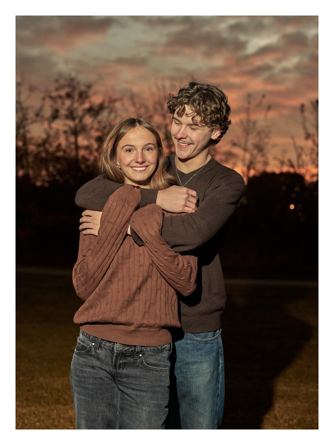 A couple embracing outdoors under a colourful evening sky