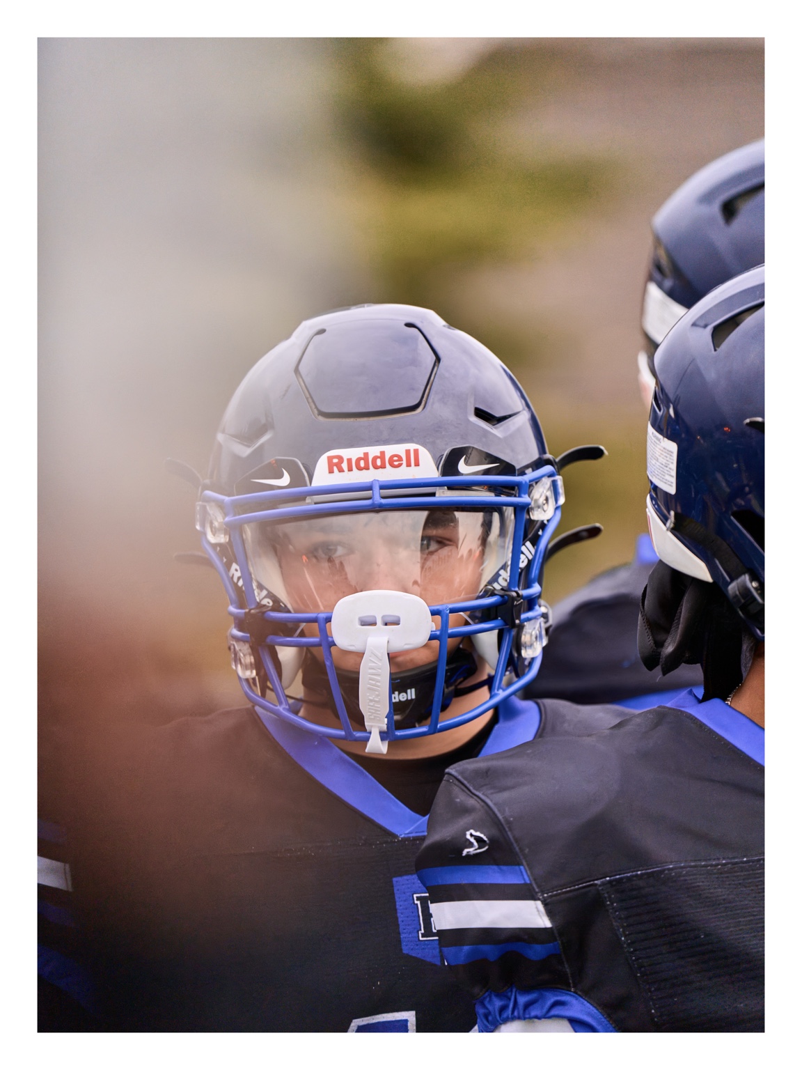 Close portrait of a helmeted football player on the sideline