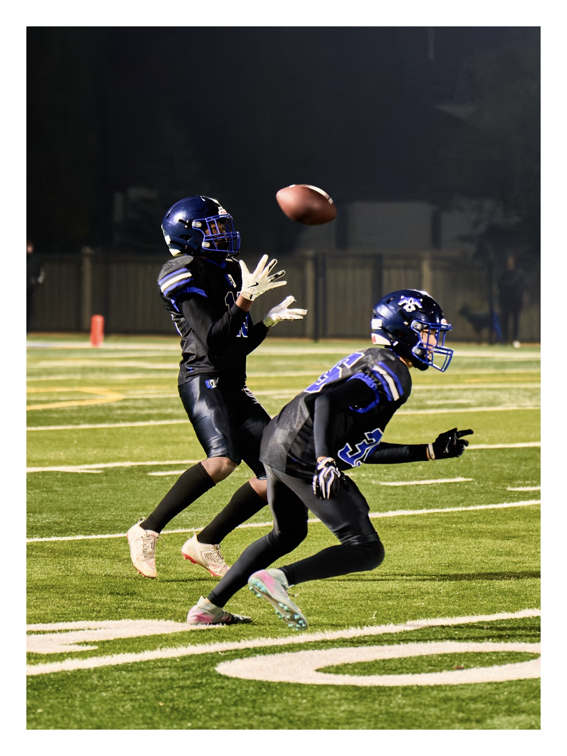 Football receiver reaching for a pass under the field lights